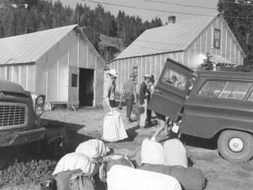 A black-and-white photograph of students unloading duffel bags with their belongings.